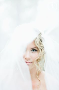 a woman wearing a white veil and posing for a photo with her hair in the wind