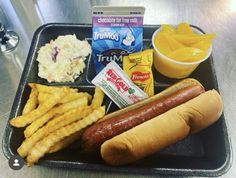 a hot dog, french fries, potato chips and milk on a tray with condiments