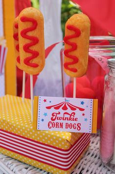 there are two hot dogs on sticks with condiments in front of the table