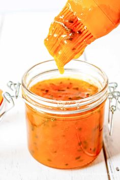 a jar filled with orange sauce being drizzled over it