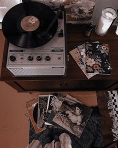 a record player sitting on top of a wooden table next to a pile of cds