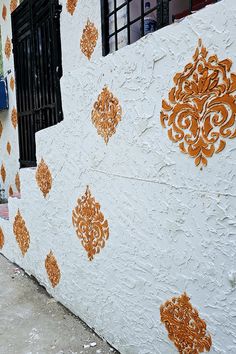 an orange and white wall with ornate designs painted on it's side, next to a fire hydrant