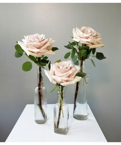 three vases with roses in them on a table