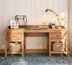 a wooden desk with two baskets underneath it and a lamp next to it on top