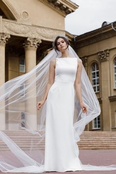 a woman wearing a wedding dress and veil standing in front of a building with stairs