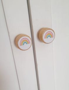 two wooden knobs on the side of a door with a rainbow painted on them