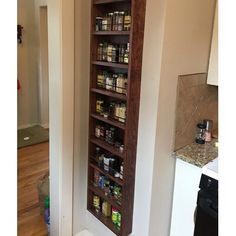 a tall wooden spice rack in the corner of a kitchen