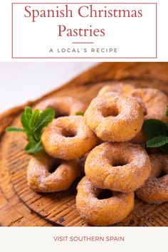 a wooden plate topped with donuts covered in sugar and sprinkled with green leaves