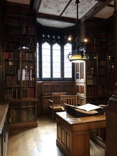 an old library filled with lots of books and wooden desks next to a window