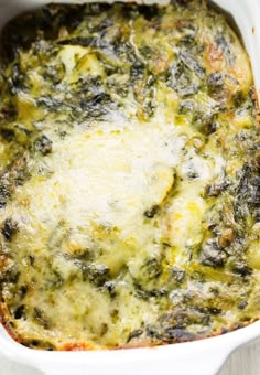 a casserole dish with spinach and cheese in it sitting on a table