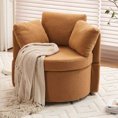 a round chair with pillows and a blanket on the floor in front of a window