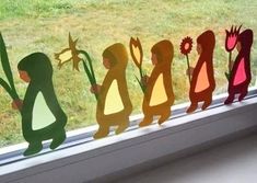 a group of paper cut outs sitting on top of a window sill next to a grass field