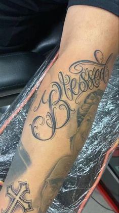 a man with a cross tattoo on his arm and the word jesus written in cursive font