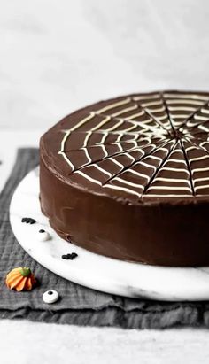 a chocolate cake sitting on top of a white plate with spider web decoration around it