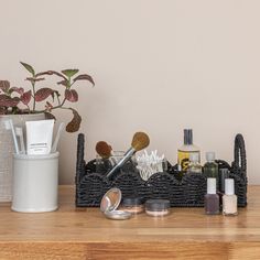 a wooden table topped with lots of makeup and personal care items next to a potted plant