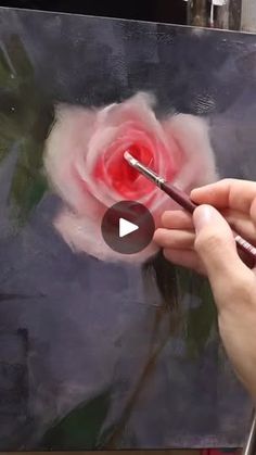 a person is painting a flower on a canvas