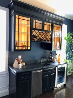 a kitchen with black cabinets and stainless steel dishwasher in the center, next to a potted plant