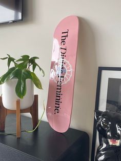 a pink skateboard sitting on top of a black table next to a potted plant