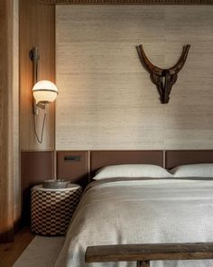 a large bed sitting under a light next to a wall mounted deer's head