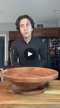 a man standing in front of a wooden bowl on top of a counter next to a refrigerator