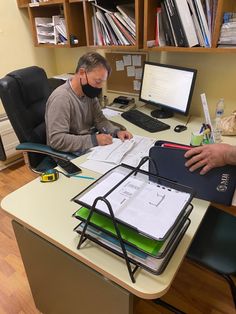 two men sitting at a desk working on paperwork