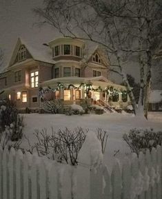 a large house is lit up at night in the snow