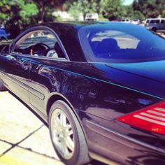 the back end of a black car parked in a parking lot