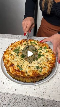 a woman cutting into a pizza on top of a white plate