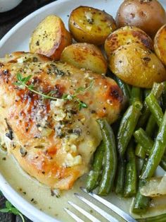 a white plate topped with chicken, potatoes and green beans