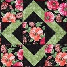 a black and pink flowered quilt with green squares on the bottom, along with red flowers