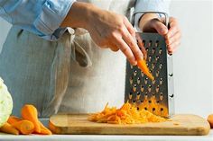 a person grating carrots with a grater on top of a cutting board