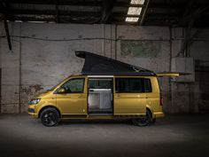 a yellow van is parked in an empty garage with its door open and the roof opened