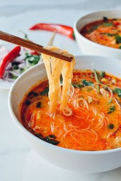 two bowls of soup with chopsticks sticking out of one bowl and another bowl in the other