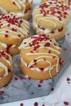 some tasty looking pastries with white icing and red sprinkles