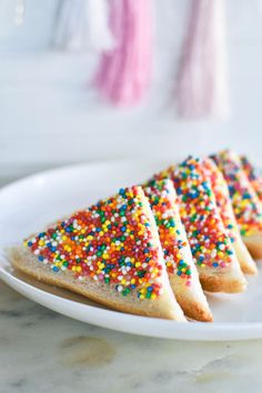 four pieces of cake on a plate with sprinkles and the words fairy bread