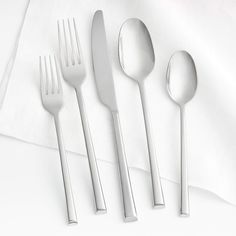 four forks, two spoons and one knife on a white tablecloth with a napkin