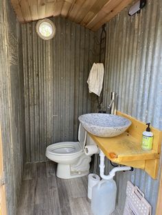 a toilet and sink in a small room with corrugated siding on the wall behind it