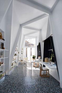 an office with white walls and flooring is seen from the hallway to the living room