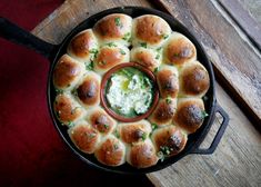 a pan filled with rolls and dip on top of a wooden table