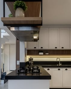 a kitchen with white cabinets and black counter tops is seen in this image, there are plants on the shelf above the stove