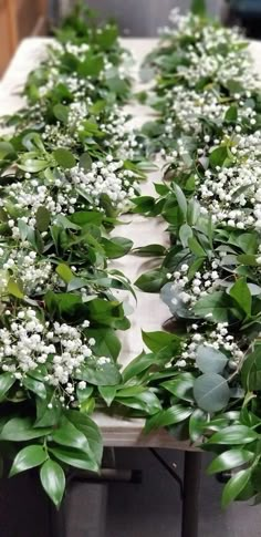 the table is covered with white flowers and green leaves on it's sides,