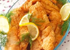 fried fish with lemons and dill garnish in a glass dish