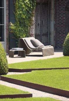 an outdoor lounge chair in the middle of a garden