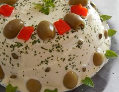 a cake with white frosting and olives on top is decorated with green leaves