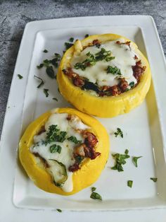 two stuffed peppers with cheese and herbs on a white plate