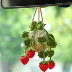 a crocheted bag hanging from the side of a car's dashboard with strawberries attached to it