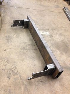 two metal brackets sitting on top of a cement floor next to a piece of machinery