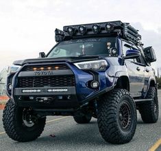 a blue toyota truck with lights on driving down the road