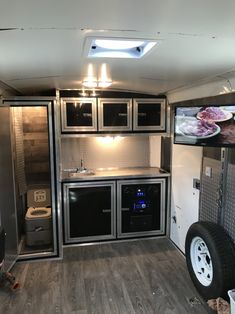 the inside of an rv with wood flooring and stainless steel cabinets, including ovens