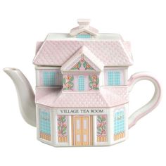 a teapot shaped like a house with a pink roof and flowers on the front